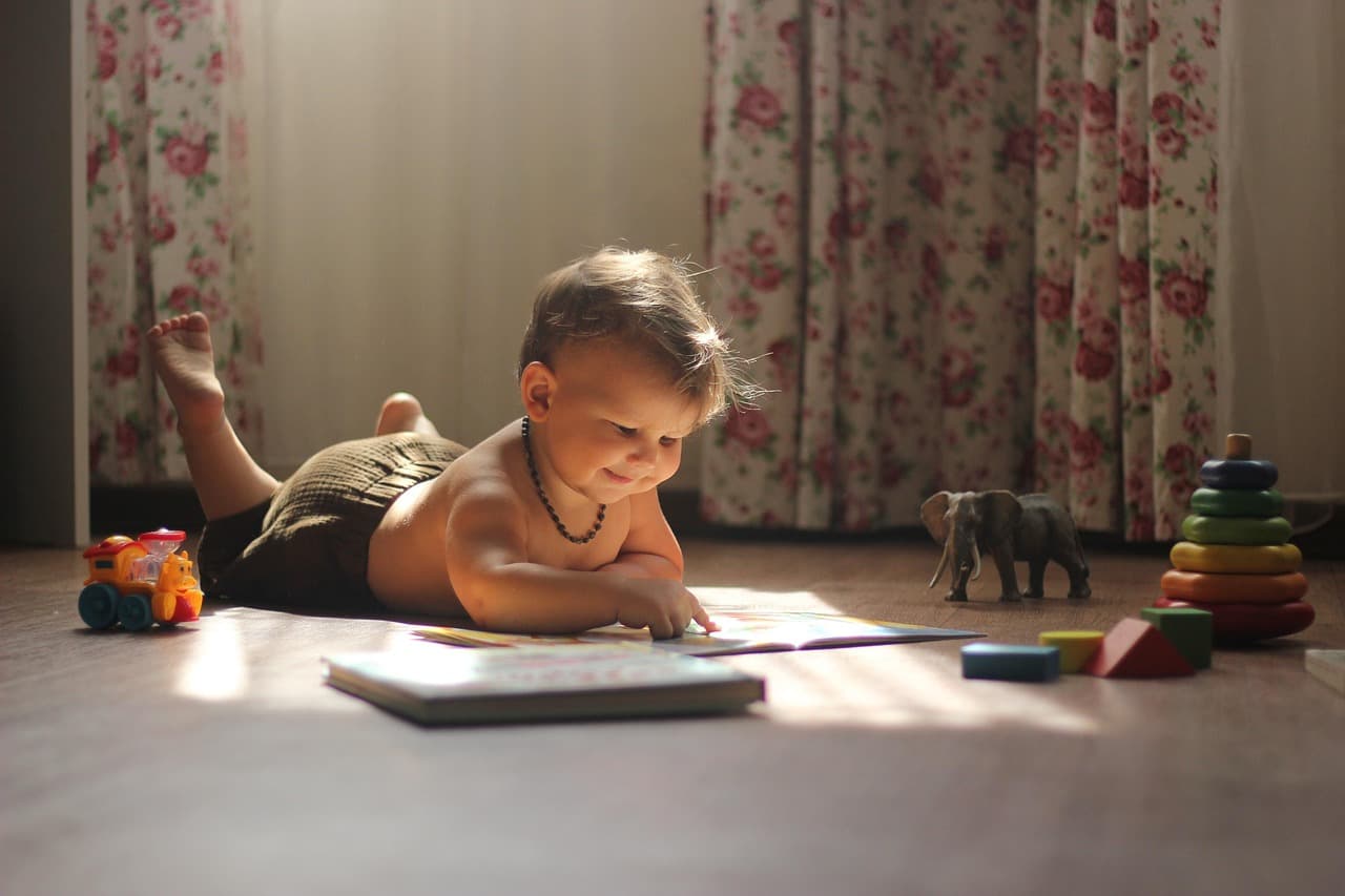 Pediatrician sitting on the floor at child's level, making eye contact with a toddler during a developmental assessment