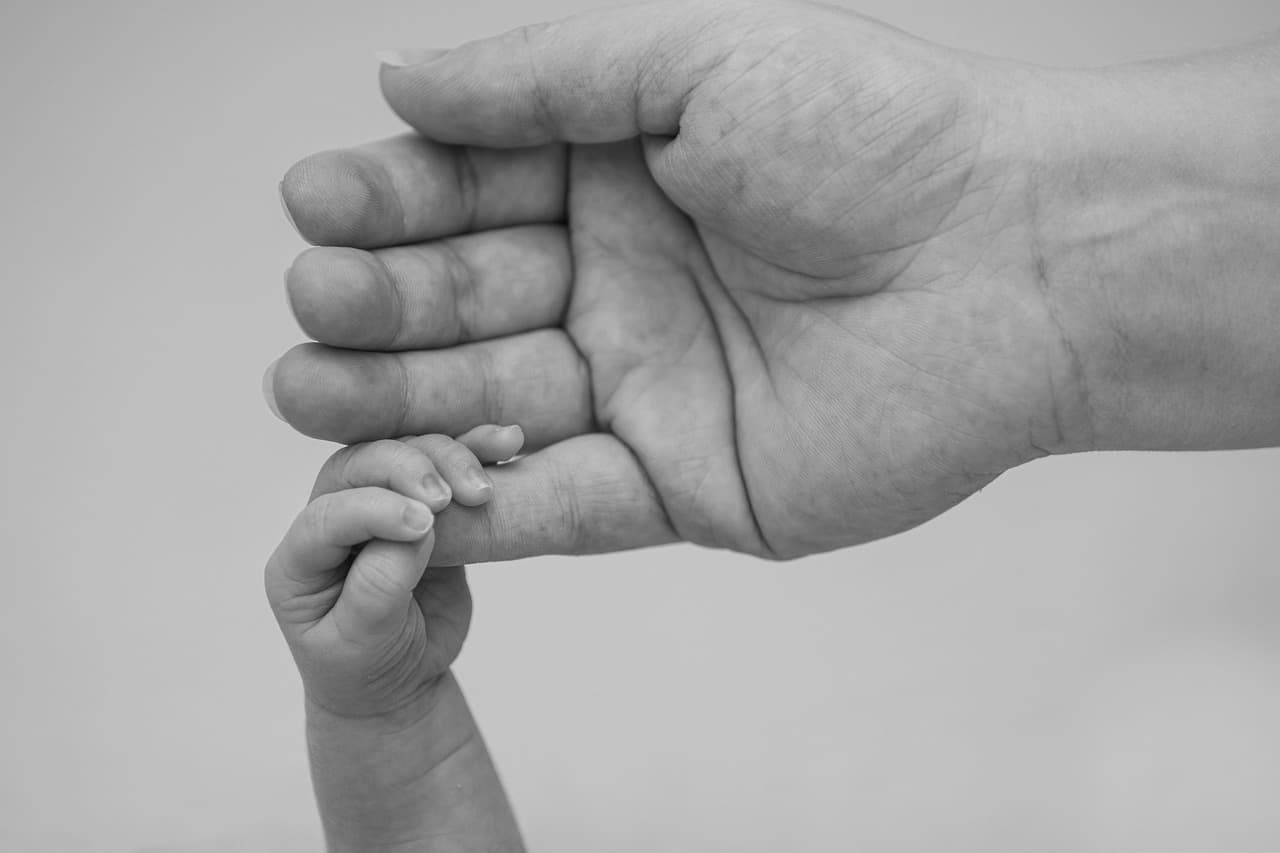 Parent gently applying barrier cream during a diaper change, close-up of careful newborn skin care